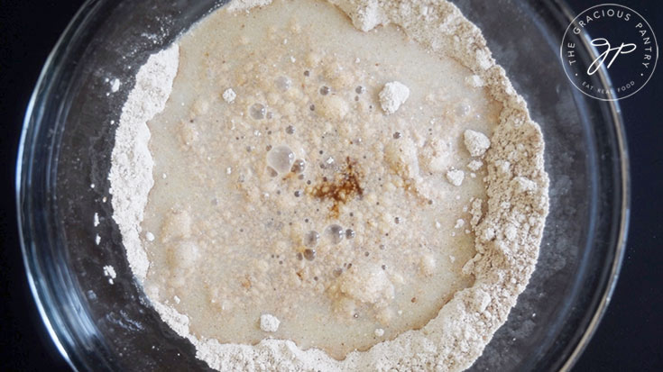 Milk and vanilla added to a flour mixture in a mixing bowl.