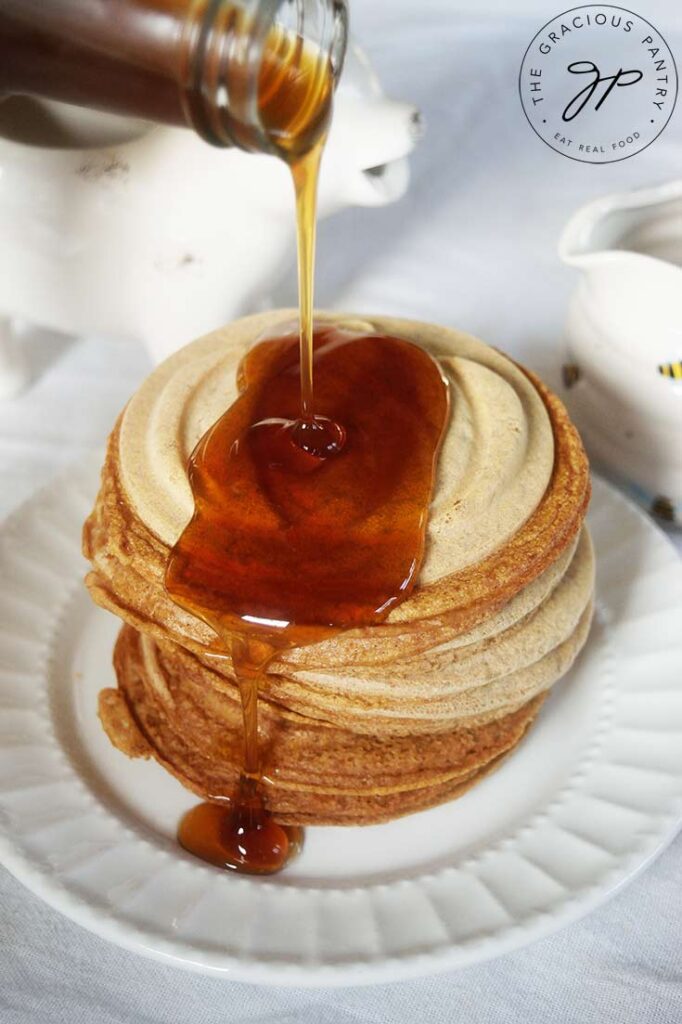 Maple syrup pouring over a stack of Pumpkin Spice Pancakes.