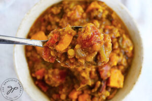 A spoon lifts a spoonful of Slow Cooker Lentil Stew out of a bowl.