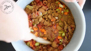 Stirring Slow Cooker Lentil Stew Recipe ingredients in a slow cooker crock.