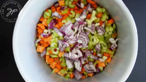 Onions, celery, carrots, sweet potatoes and lentils in a slow cooker crock.