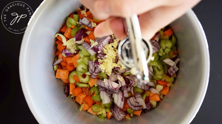 Pressing garlic cloves into a crock.