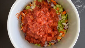 Dice tomatoes added to a slow cooker crock.