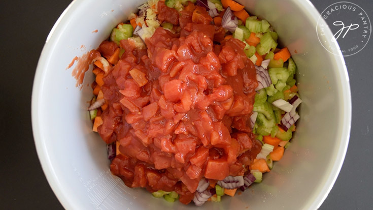 Dice tomatoes added to a slow cooker crock.