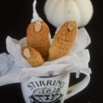 Three witch finger cookies nestled in crinkled parchment inside of a halloween mug.