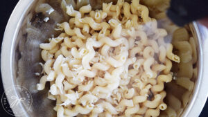 Spraying cooked pasta with an oil sprayer.