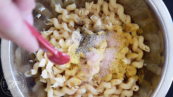 Adding salt to a mixing bowl with pasta.