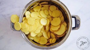 Sliced potatoes in a metal pot.