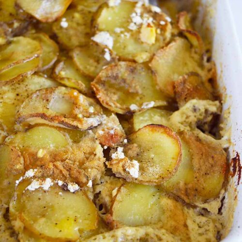 A side view of a white casserole dish filled with Healthy Scalloped Potatoes.