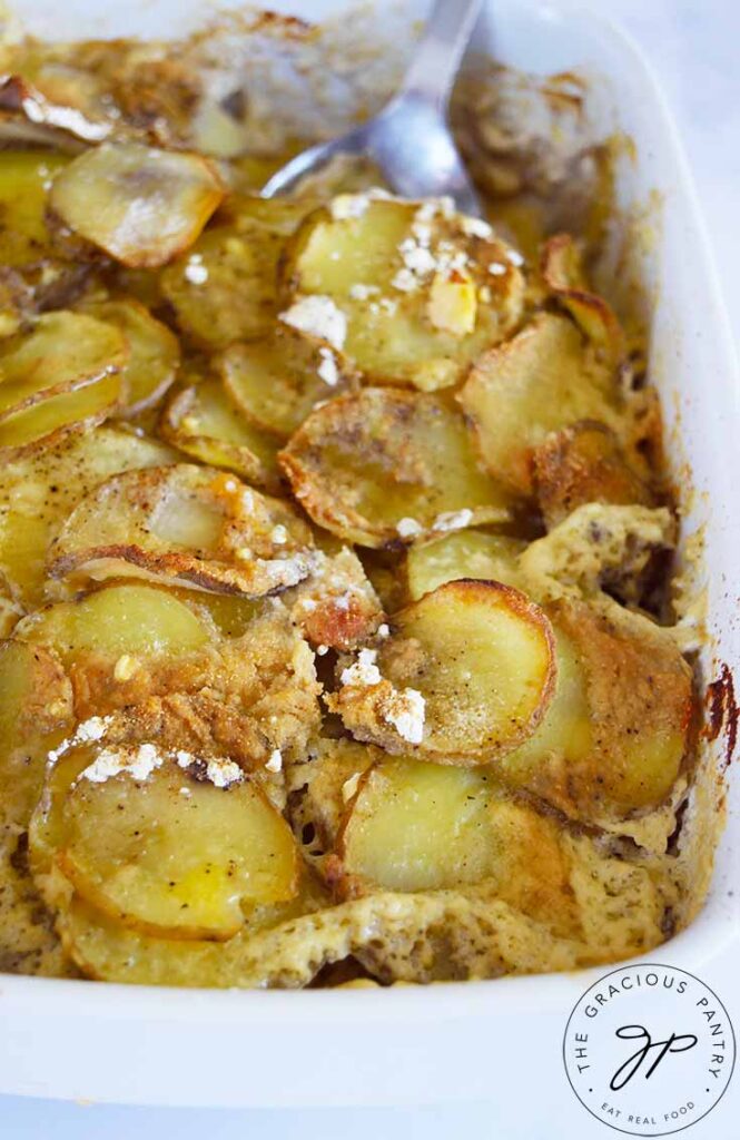 A side view of a white casserole dish filled with Healthy Scalloped Potatoes.