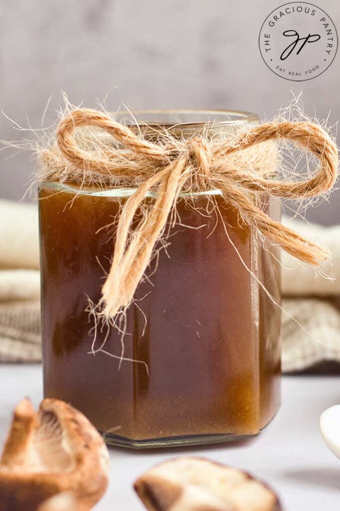 A glass jar filled with homemade fish sauce and tied off with a thin rope at the top of the jar.