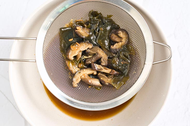 A sieve strains off solids from homemade fish sauce.