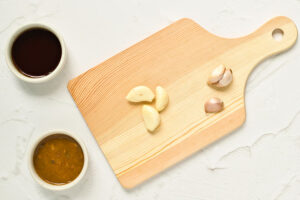 Garlic cloves being peeled, laying on a cutting board.
