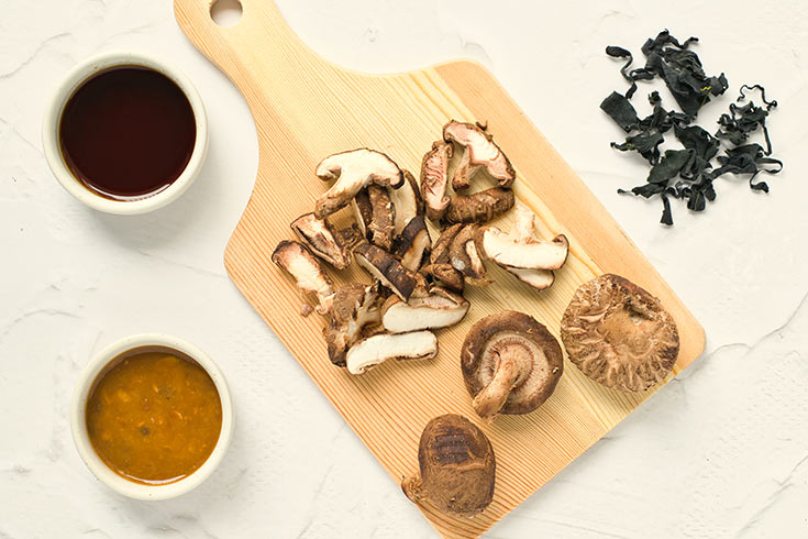 Sliced mushrooms laying on a cutting board.