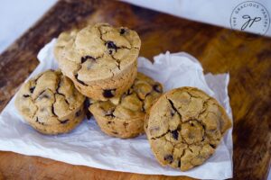 Four just-baked Pancake Muffins lay on a piece of white parchment paper.