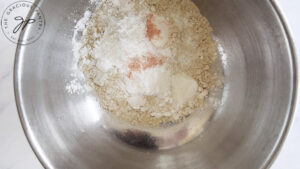 Flour and other dry ingredients sitting in a mixing bowl, unmixed.