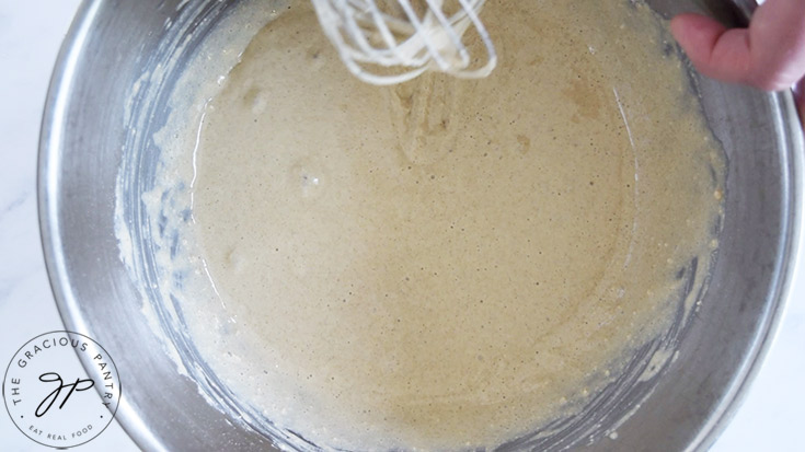 Whisked pancake batter in a metal mixing bowl.