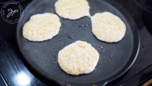 4 pancakes ladled onto a hot skillet.