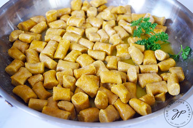 A pan full of Pumpkin Gnocchi with a bit of fresh parsley on the side.