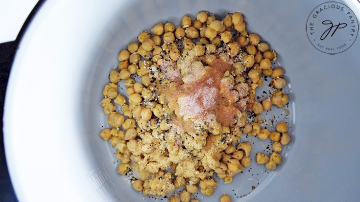 Chickpeas and seasoning with oil sitting in a mixing bowl.