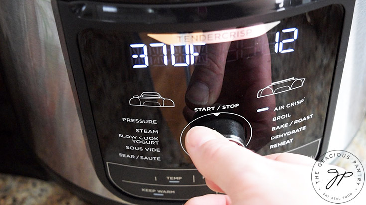 Setting an air fryer to 370 degrees F. and the timer to 12 minutes.