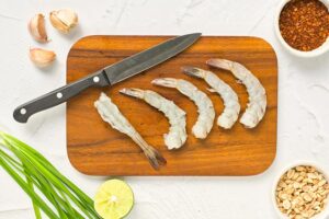 Preparing the shrimp for cooking, 5 large shrimp lay on a cutting board.