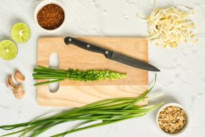 A cutting board holds chopped chives.