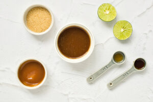 Shrimp Pad Thai sauce ingredients in individual bowls on a white surface.