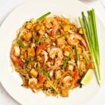 An overhead close up of a white plate filled with Shrimp Pad Thai.