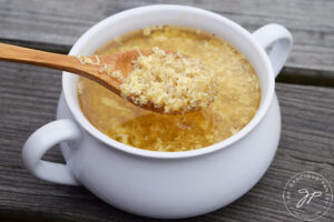 Sick Day Soup in a white bowl with a wooden spoon holding a spoonful of the soup.