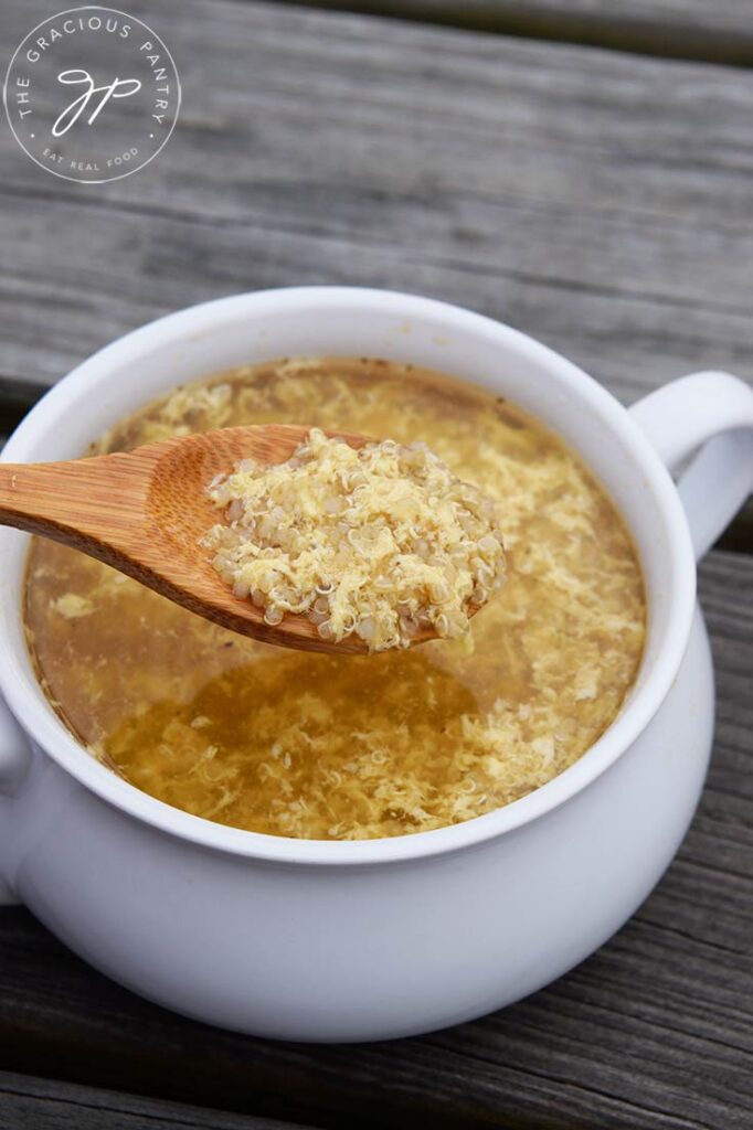 A spoon lifts a bit of sick day soup out of a white bowl.