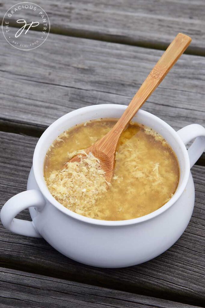 A white bowl filled with sick day soup sits on a wooden surface.