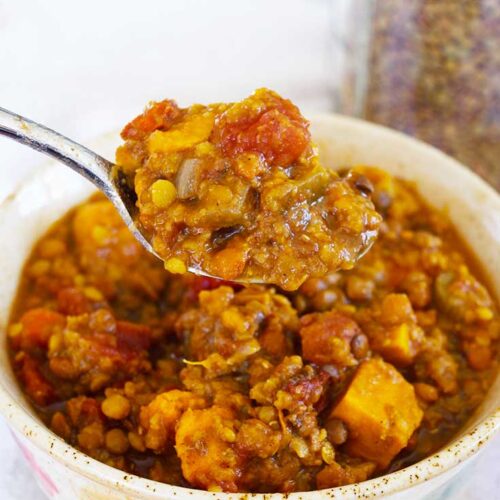 A spoonful of Slow Cooker Lentil Stew held up over a bowl of the same.