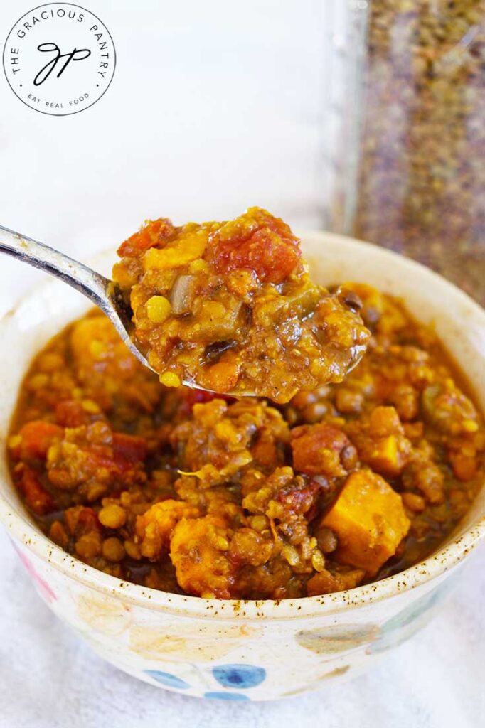 A spoonful of Slow Cooker Lentil Stew held up over a bowl of the same.