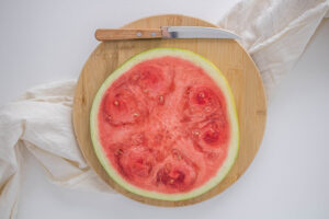 A round slice of watermelon on a cutting board.