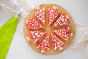 8 Watermelon Christmas Trees on a cuttong board decorated with yogurt.