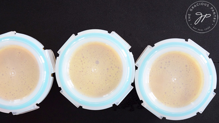 Three glass, oven-safe containers filled with raw egg mixture with lids on.