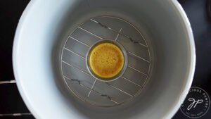 A glass, oven-safe container with lid removed, sitting in an air fryer basket.