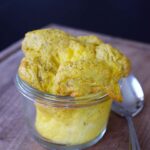 A side view of a glass container holding Air Fryer Scrambled Eggs.