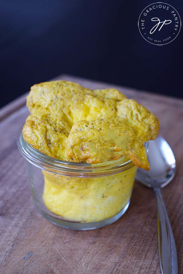 A side view of a glass container holding Air Fryer Scrambled Eggs.