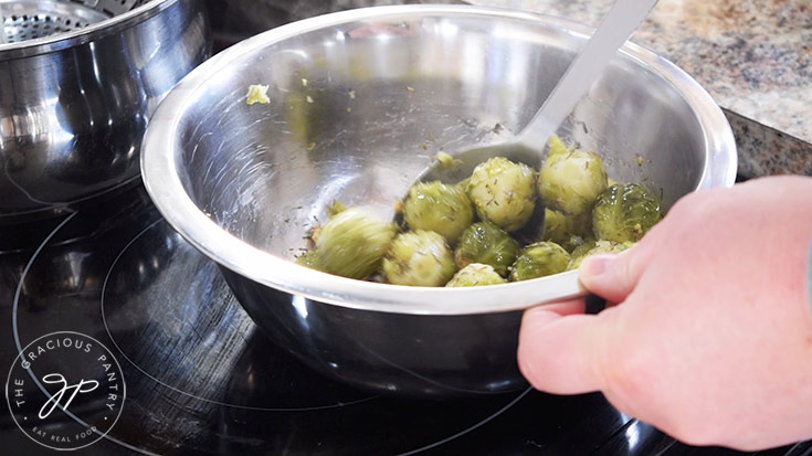 Stirring together the brussels sprouts and spices in a mixing bowl.