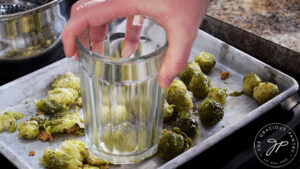 Smashing cooked brussels sprouts with a glass cup.