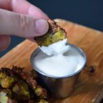 A hand dipping an Air Fryer Smashed Brussel Sprout into ranch dip.