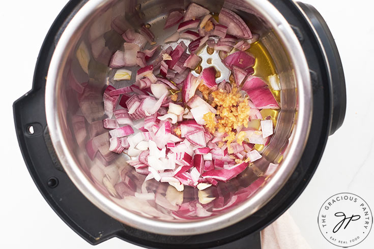 Onions garlic and oil sautéing in an Instant Pot.