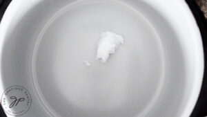 A tablespoon of coconut oil in a pot.