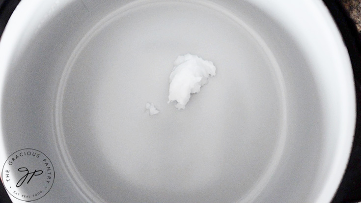 A tablespoon of coconut oil in a pot in preparation for making chicken curry soup.