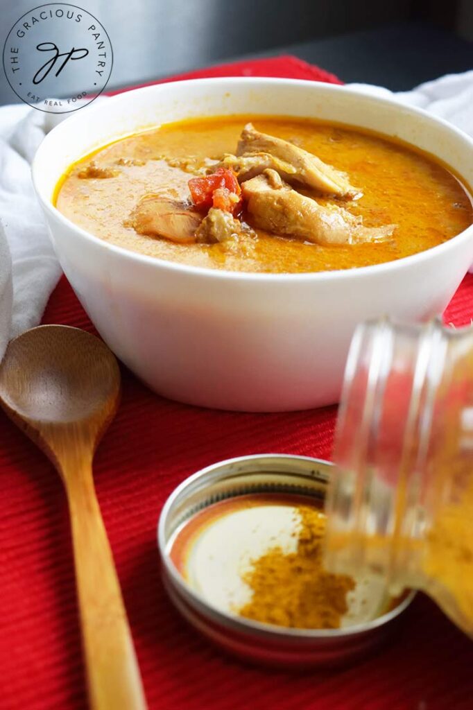 A low angle shot of a white bowl filled with chicken curry soup.