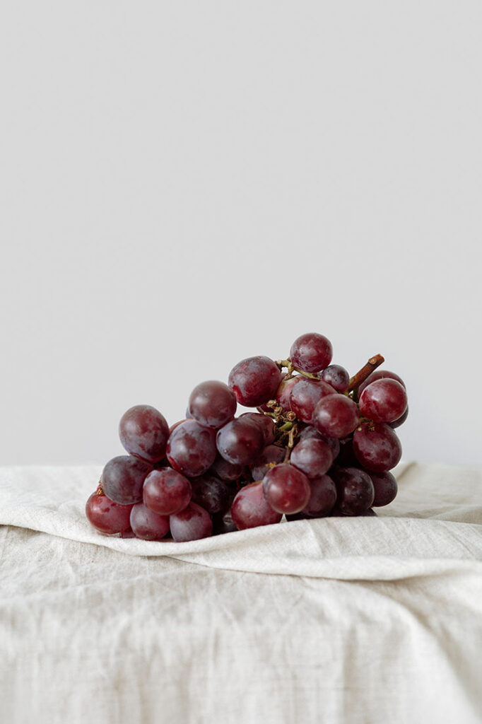 A bunch of red grapes on an offwhite tablecloth.