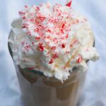 A side view of a Homemade Peppermint Mocha topped with whipped cream and crushed candy cane.