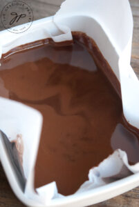 Melted mint chocolate chip "batter" poured into a parchment-lined casserole dish.